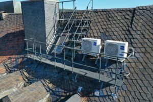 Stabile Dachbegehungsanlage mit Treppe und Geländer sorgt für sicheren Zugang zwischen Dachflächen und Klimageräten.
