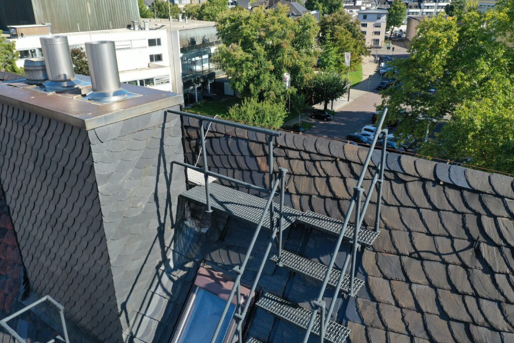 Dachtreppe mit Geländer führt sicher zu den Schornsteinaufbauten und erleichtert Wartungsarbeiten auf dem Schieferdach.