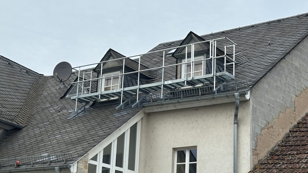 Verzinkter Dachlaufsteg mit Sicherheitsgeländer auf einem Schieferdach montiert.