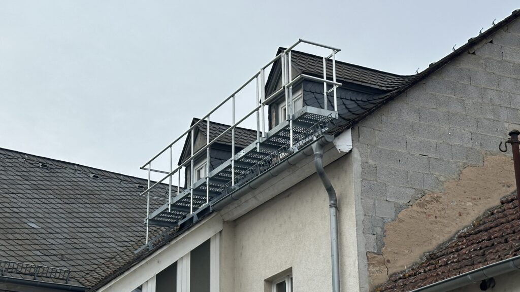 Stabile Konstruktion: Der Laufsteg bietet durch das hohe Geländer optimale Absturzsicherung und ermöglicht das sichere Arbeiten an der Fassade und den Fenstern.
